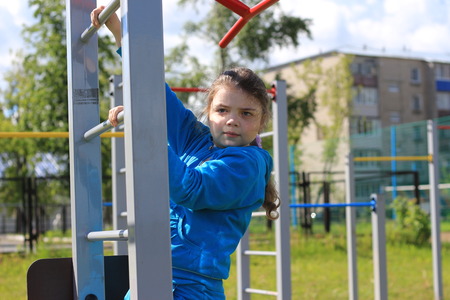 The girl does exercises at sports equipment