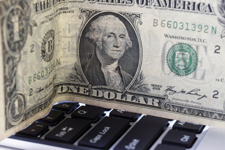 One dollar lying on a computer keyboardの写真素材
