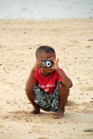 Krabi, Thailand, December 28, 2011 - Little boy with camera on the beach in Thailandのeditorial素材