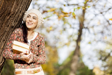 Young woman with books in the autumn forestの写真素材