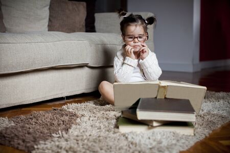 Little girl reading in the roomの写真素材