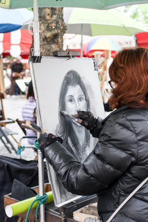 Unidentified woman drawing a portrait of the tourist at Place du Tertre at September 16, 2013. Place du Tertre is now an open-air workshop with its 288 official painters.のeditorial素材