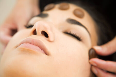 Pretty young woman having a facial stone massageの写真素材