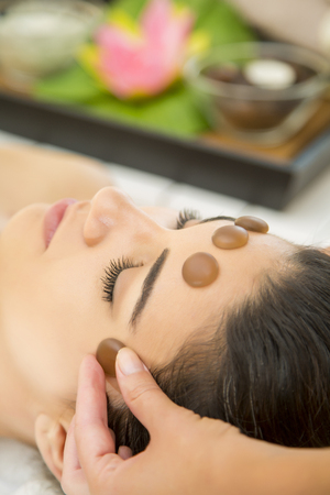 Pretty young woman having a facial stone massageの写真素材