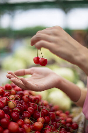 Young woman buying cherries at the market