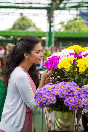 Young woman buying flowers at marketの写真素材