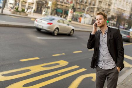 Young man on the street with mobile phoneの写真素材