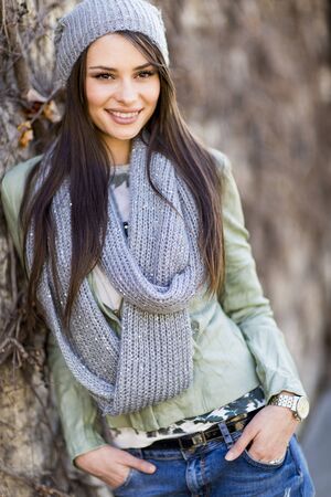Young woman by the wall at autumnの写真素材