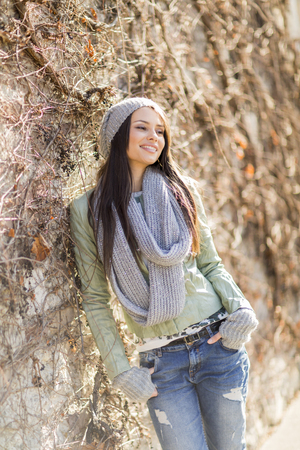 Young woman by the wall at autumnの写真素材