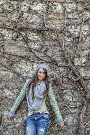 Young woman by the wall at autumnの写真素材