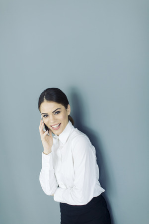 Young woman with mobile phone by the wallの写真素材