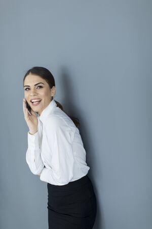 Young woman with mobile phone by the wallの写真素材