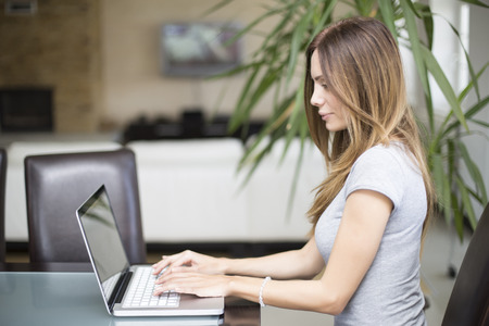 Young woman working on laptop in the roomの写真素材
