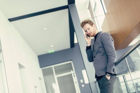 Young man with mobile phone in the officeの写真素材