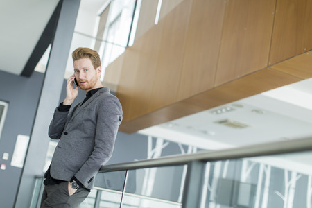 Young man with mobile phone in the officeの写真素材