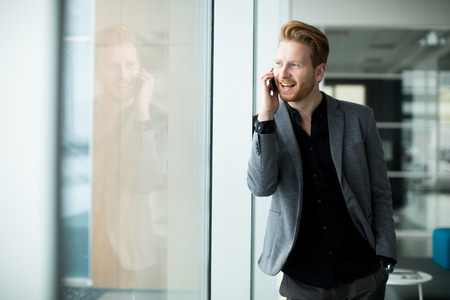 Young man with mobile phone in the officeの写真素材