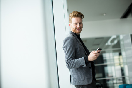 Young man with mobile phone in the officeの写真素材