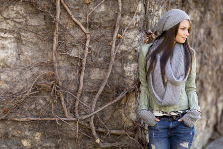 Young woman by the wall at autumnの写真素材