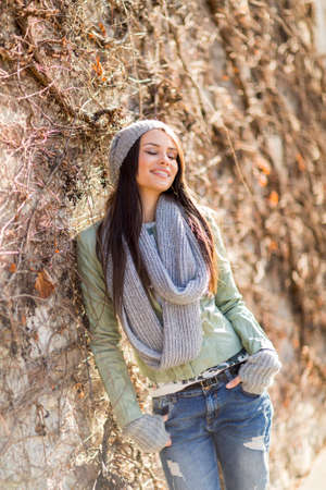 Young woman by the wall at autumnの写真素材