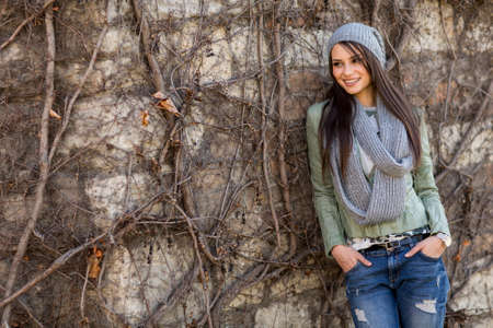 Young woman by the wall at autumnの写真素材