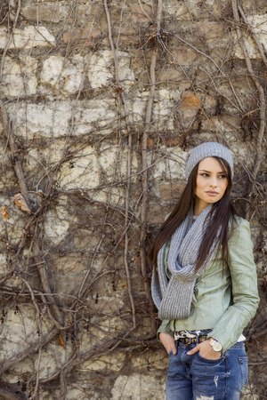 Young woman by the wall at autumnの写真素材