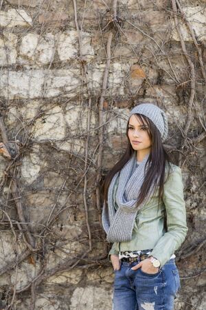Young woman by the wall at autumnの写真素材