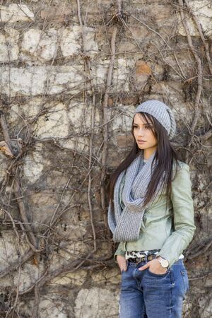 Young woman by the wall at autumnの写真素材