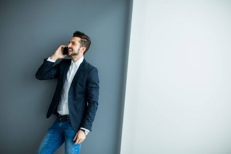 Young man with mobile phone in the officeの写真素材
