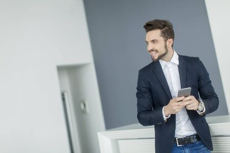 Young man with mobile phone in the officeの写真素材
