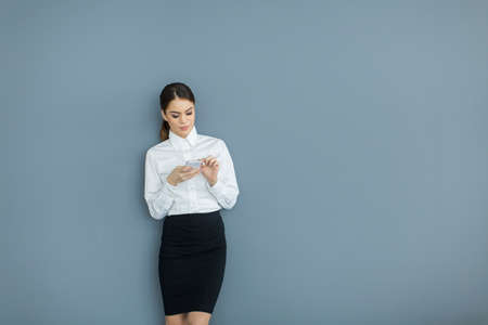 Young woman with mobile phone by the wallの写真素材
