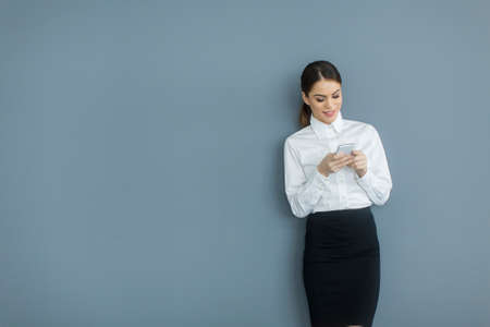 Young woman with mobile phone by the wallの写真素材