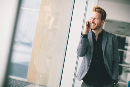 Young man with mobile phone in the officeの写真素材
