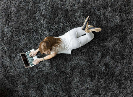 Young woman laying on the carpetの写真素材