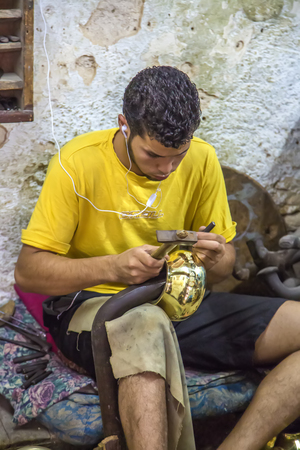 FES, MOROCCO - September 15, 2014 : Unknown man working as handcraftsman at workshop in Fes, Morocco. He makes their traditional souvenirs.のeditorial素材