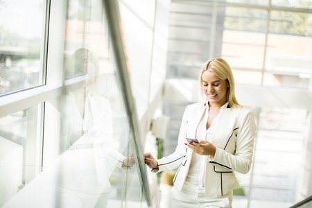 Young woman with mobile phone in the officeの写真素材