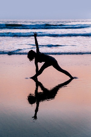Young woman practicing yoga on beach in Agonda, Goa, Indiaの写真素材