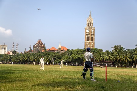 MUMBAI, INDIA - OCTOBER 10, 2015: Unidentified people playing sqiash by the Rajabai Clock Tower in Mumbai. Tower was completed at 1878 and have height of 85 m.のeditorial素材