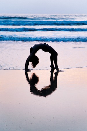 Young woman practicing yoga on beach in Agonda, Goa, India