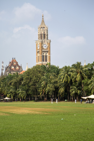 MUMBAI, INDIA - OCTOBER 10, 2015: Unidentified people playing sqiash by the Rajabai Clock Tower in Mumbai. Tower was completed at 1878 and have height of 85 m.のeditorial素材