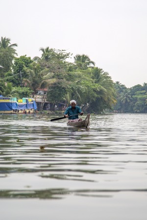 KERALA, INDIA - OCTOBER 16, 2015: Unindetified man at backwaters in Kerala, India. The backwaters are an extensive network of 41 west flowing interlocking rivers, lakes and canals that center around Alleppey, Kumarakom and Punnamada.のeditorial素材