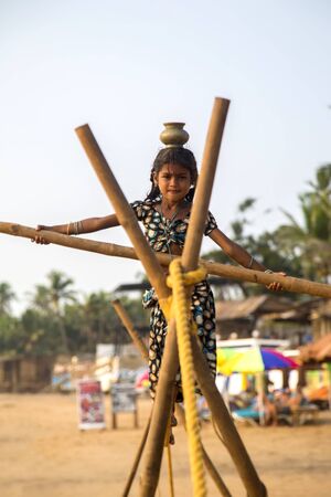 ANJUNA, INDIA - OCTOBER 14, 2015: Unidentified Goan Girl on a tightrope at the Anjuna Beach.のeditorial素材