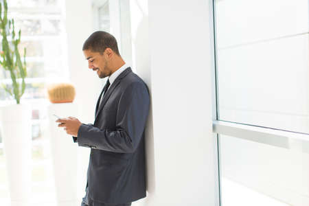 Handsome young black man with mobile phone in the officeの写真素材