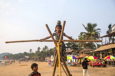 ANJUNA, INDIA - OCTOBER 14, 2015: Unidentified Goan Girl on a tightrope at the Anjuna Beach.のeditorial素材
