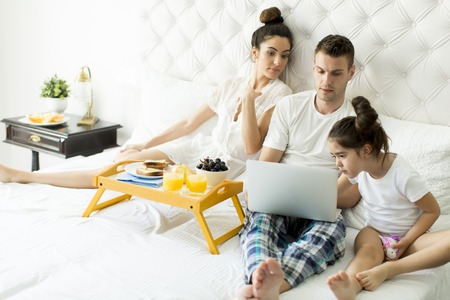 Family with little girl having breakfest in the bed.の写真素材