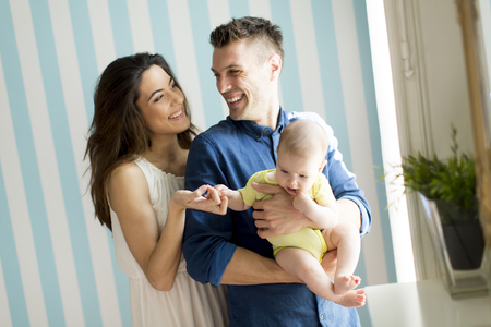Young family with a baby standing by the wallの写真素材