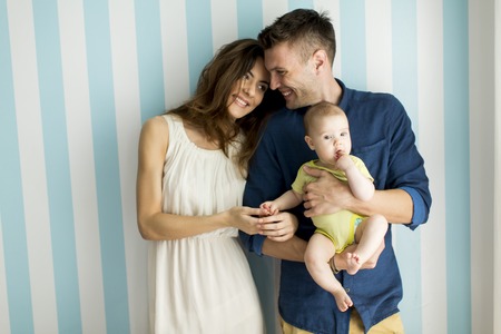 Young family with a baby standing by the wallの写真素材
