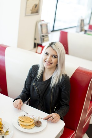 Young woman eating salad in the diner