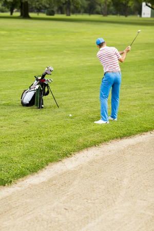 Young man playing golf at the golf courtの写真素材