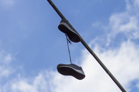 Closeup of the pair of shoes hanging by the lacesの写真素材