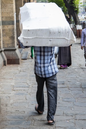 MUMBAI, INDIA - OCTOBER 9, 2015: Unidentified man carryng weight on his head. People have carried burdens balanced on top of the head since ancient times, usually to do daily work.のeditorial素材